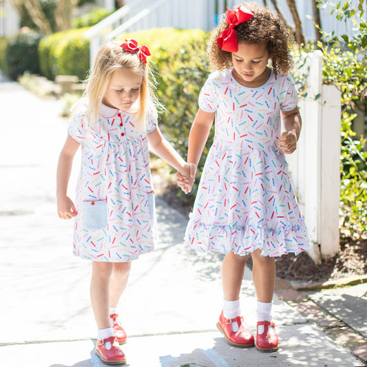 2 little girls with white dresses with crayons on them