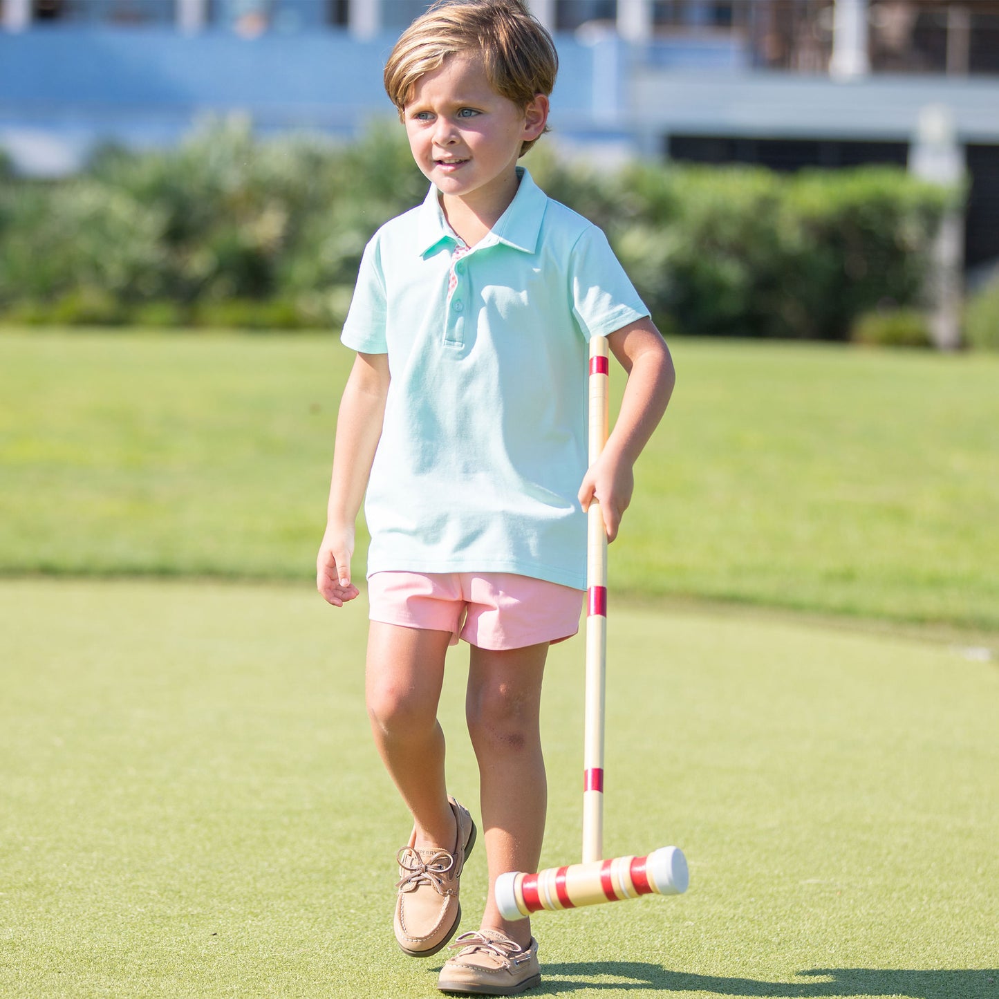 little boy holding a croquet racquet wearing an Aqua Polo Shirt