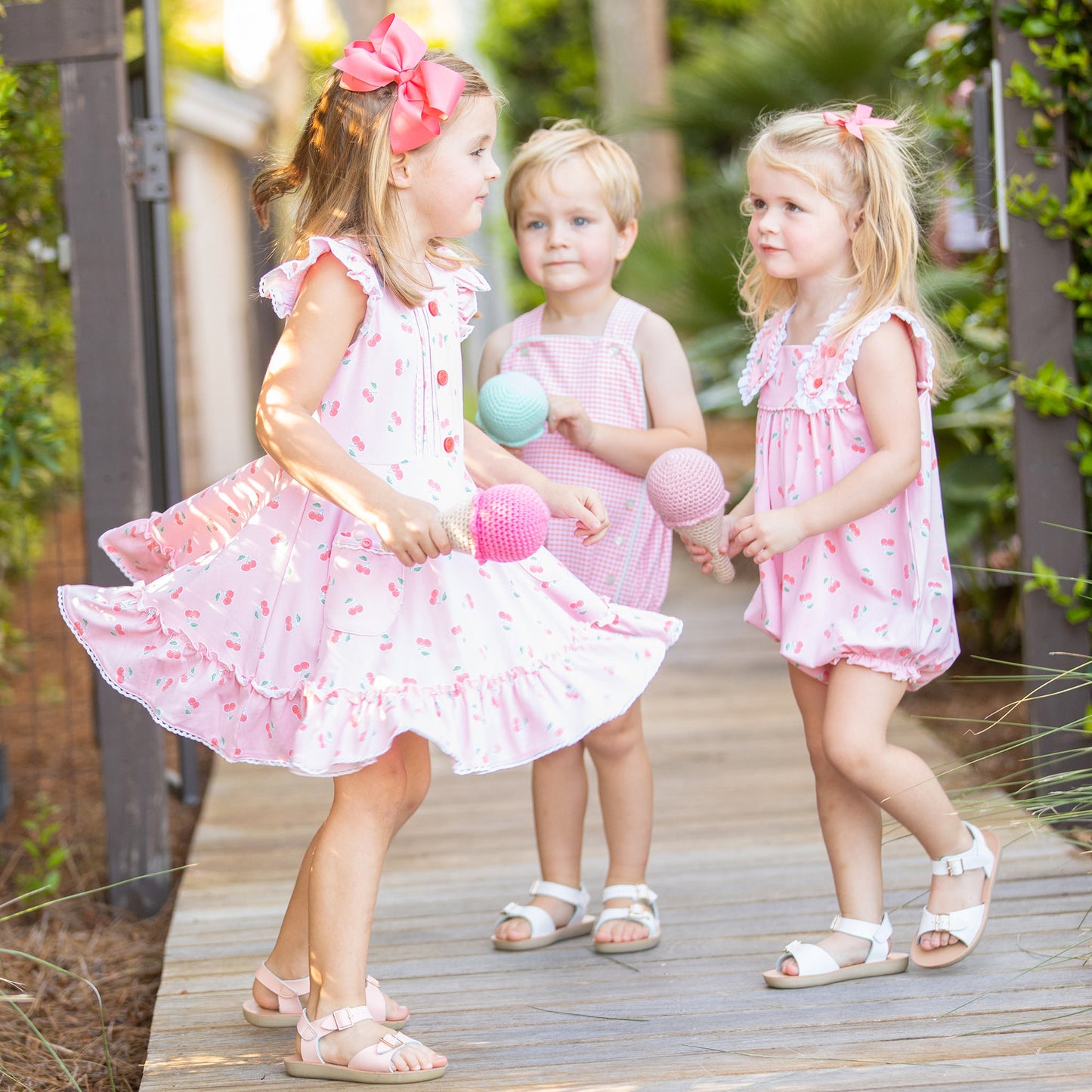 2 little girls and one little boy playing on a boardwalk with toy cloth ice cream cones
