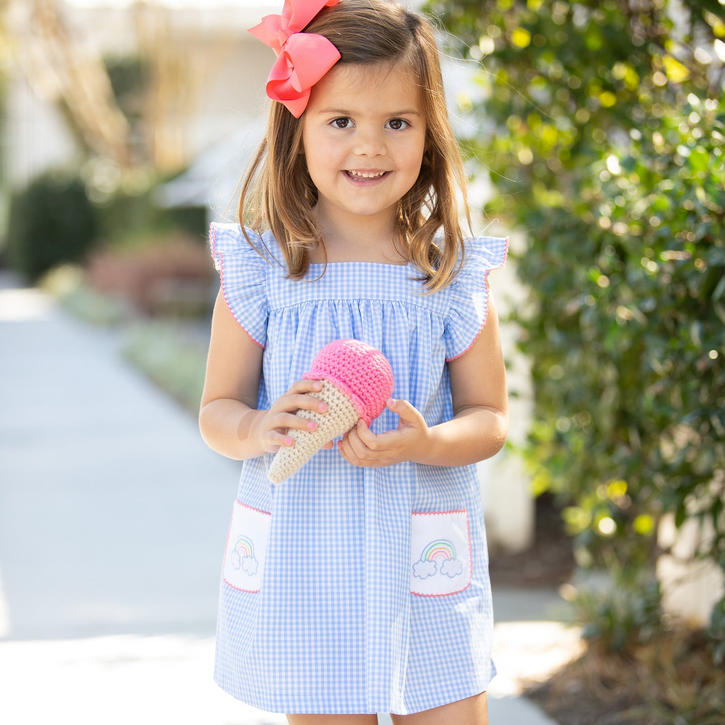 little girl wearing Sunny Rainbow Embroidered Dress standing on the sidewalk