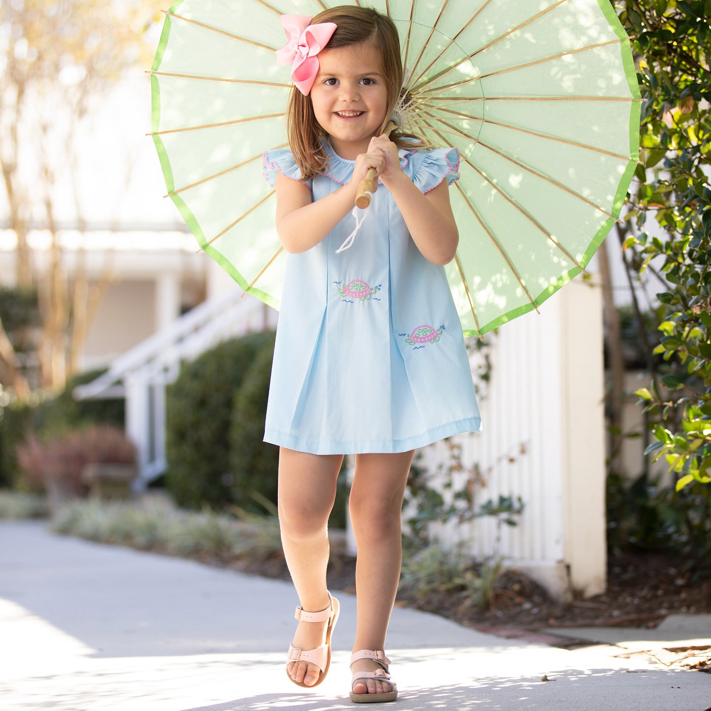 little girl in Turtles All the Way Embroidered Dress and parasol walking down the sidewalk