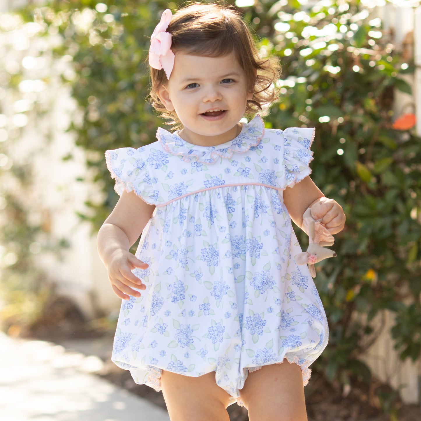little girl smiling at camera walking down a sidewalk