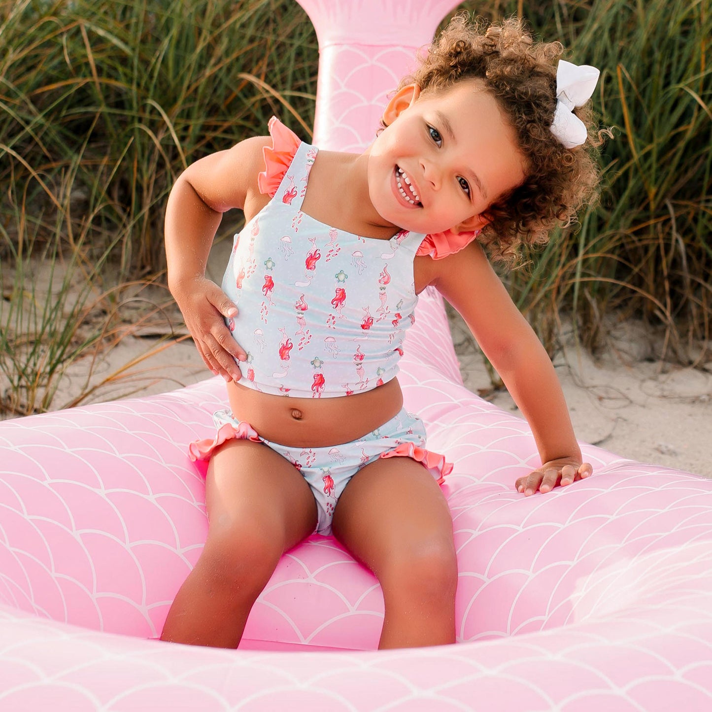 little girl sitting in a pink flamingo innertube