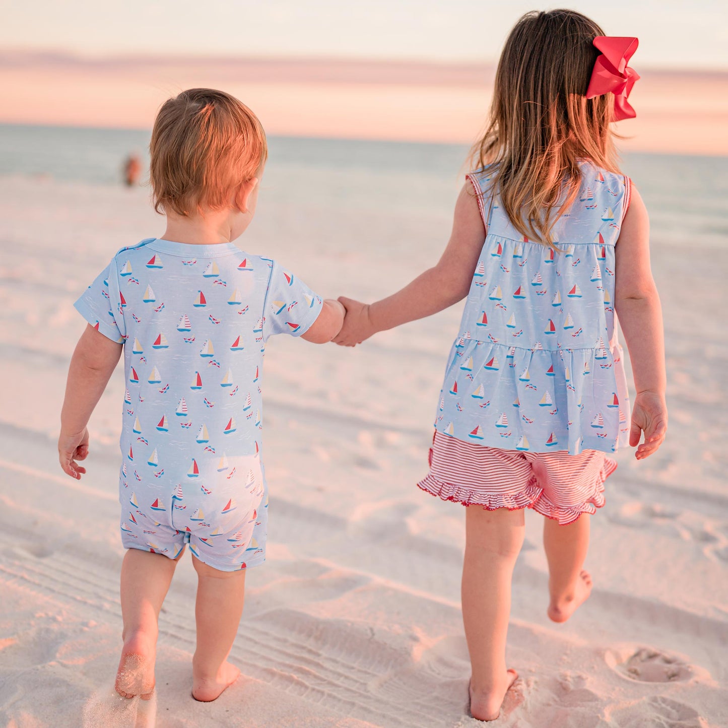little boy and baby holding hands at the beach
