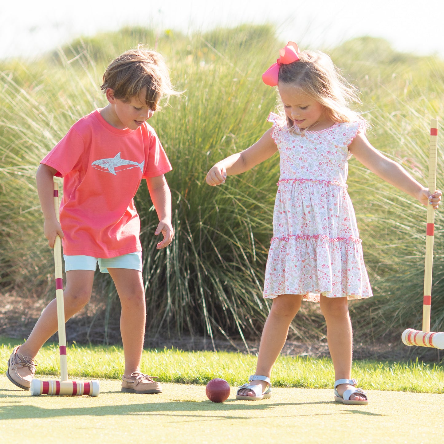 little boy wearing a Great White Graphic Tee with a little girl playing croquet