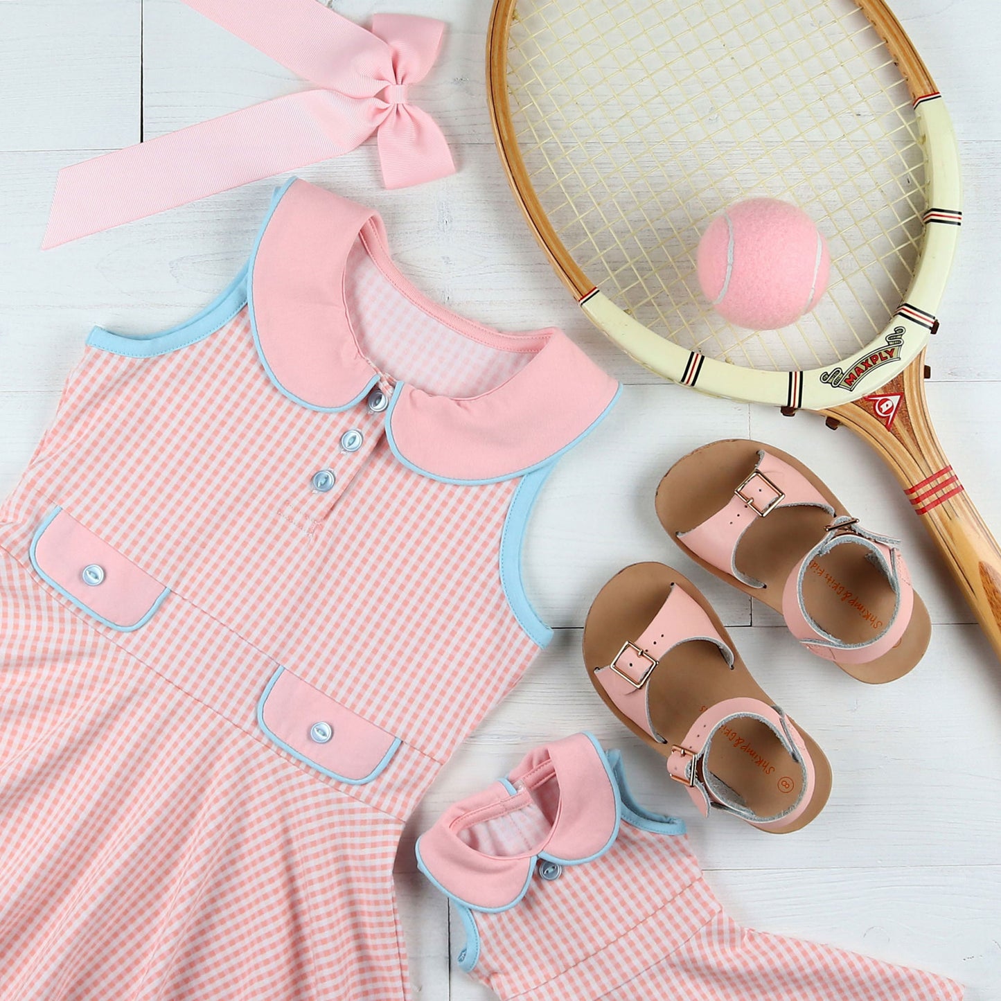 flatlay of Dress, tennis ball, tennis racket, pink bow, sandals and matching doll dress