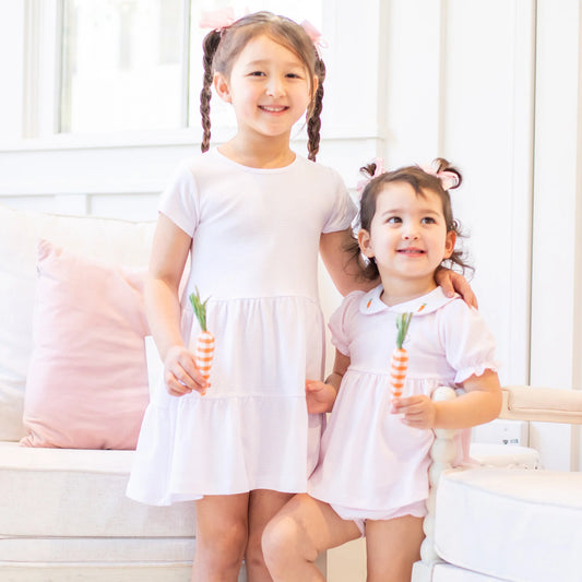sisters holding play carrots in pima cotton Easter outfits