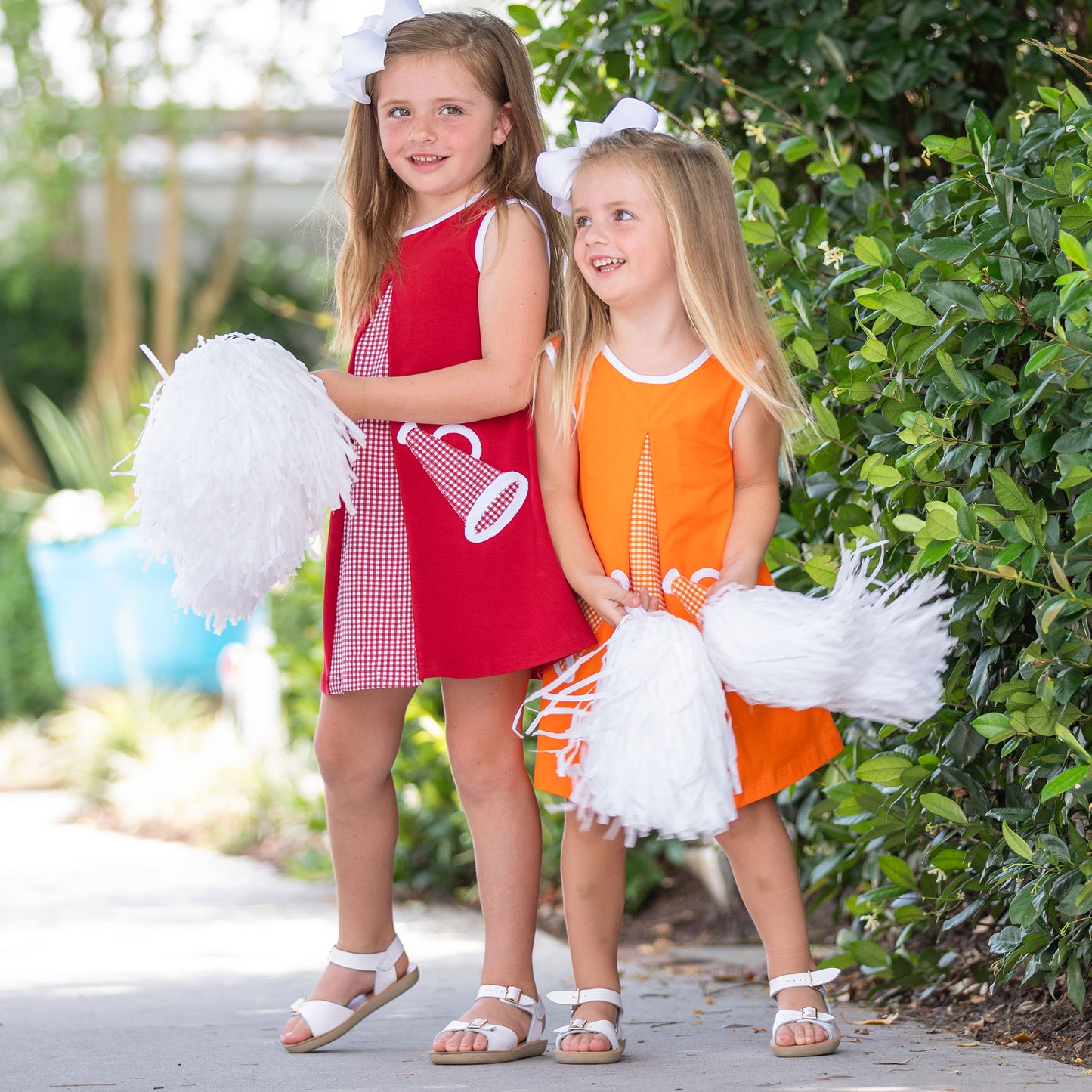 little girls in red and orange dresses with megaphones and pom poms