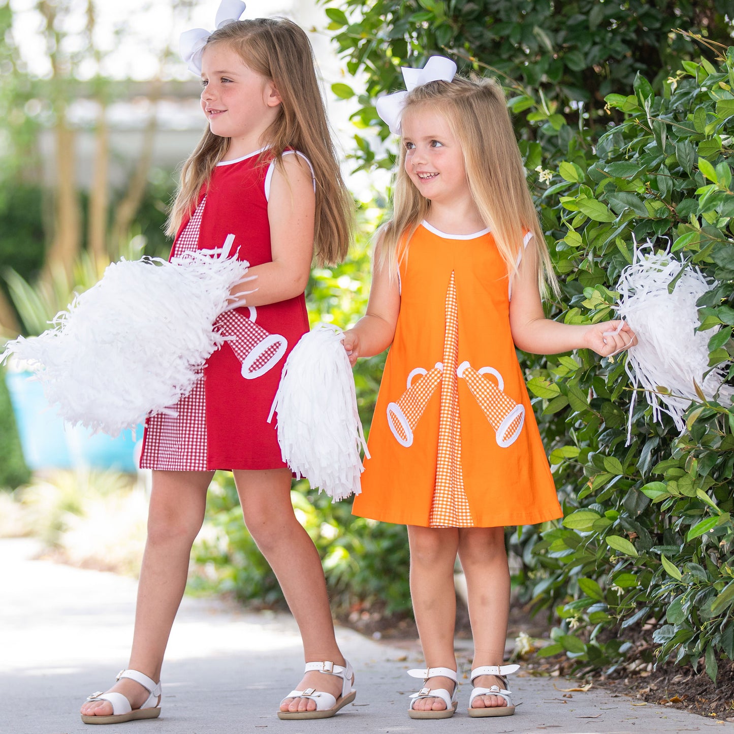 little girls in red and orange dresses with megaphones and pom poms