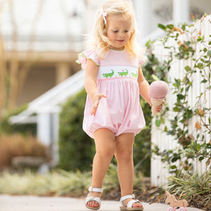 little girl playing on the sidewalk wearing Kiawah Pink Smocked Alligator Bubble