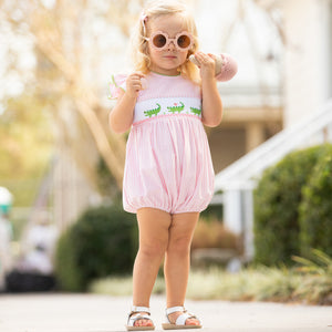 little girl walking down the sidewalk wearing sunglasses