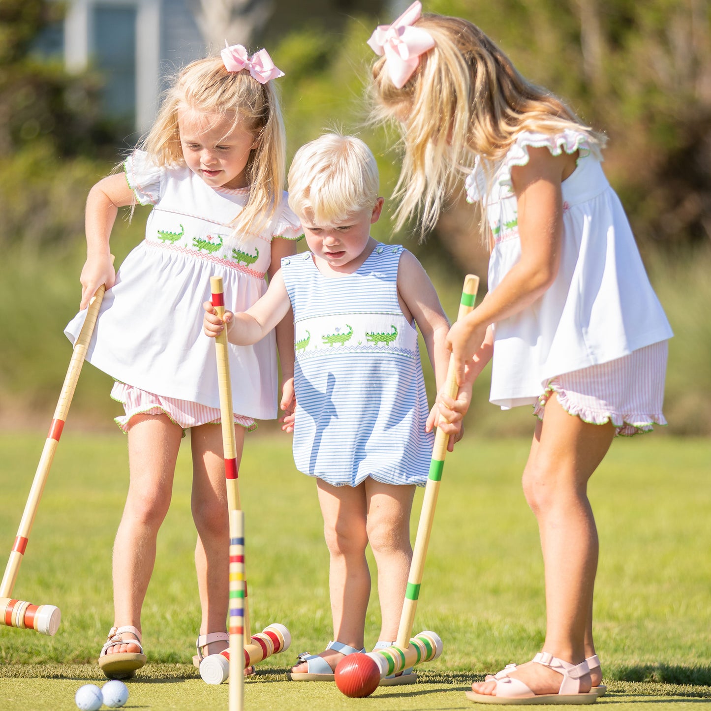 little boy and his 2 sisters playing croquet