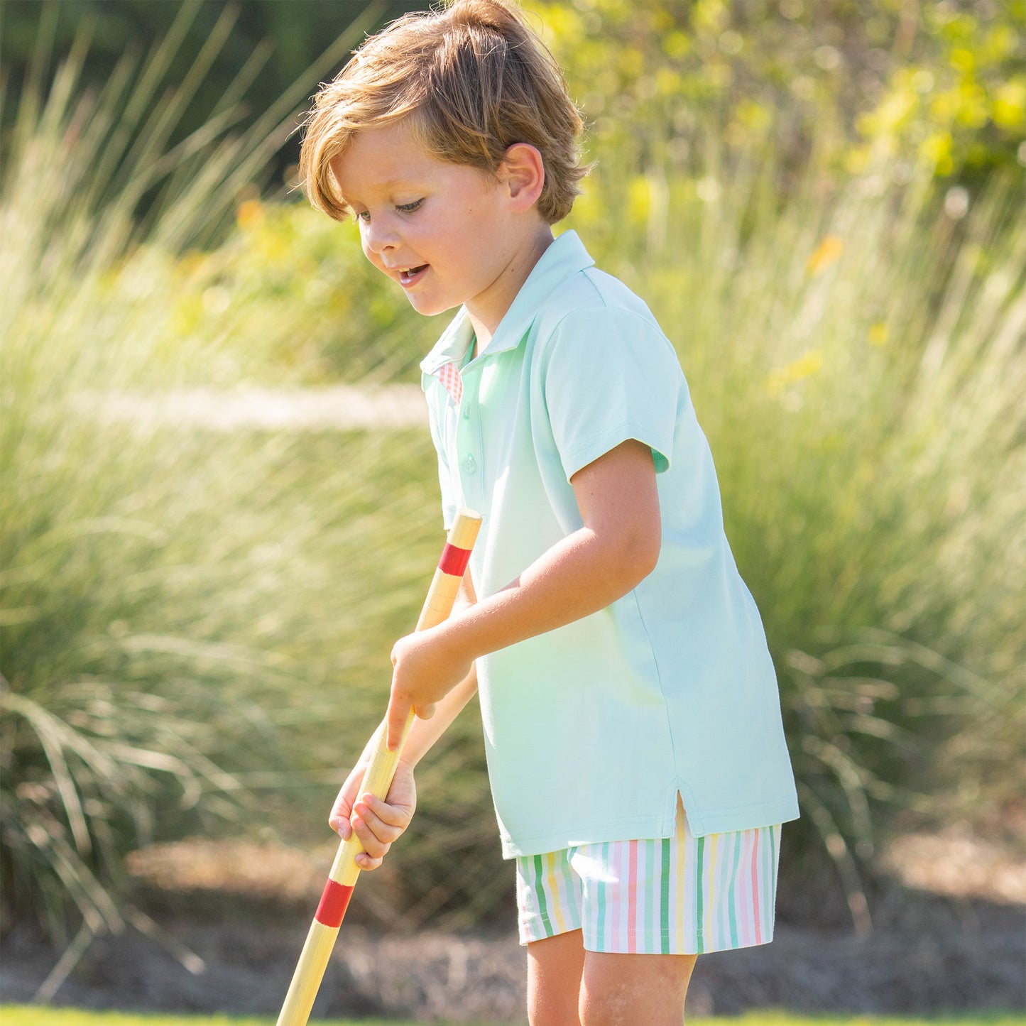 little boy playing croquet wearing an Aqua Polo Shirt