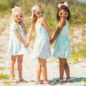three little girls in sunglasses holding hands at the beach