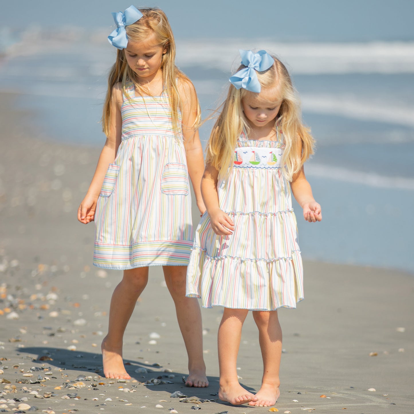 two little girls walking on the beach picking up shells