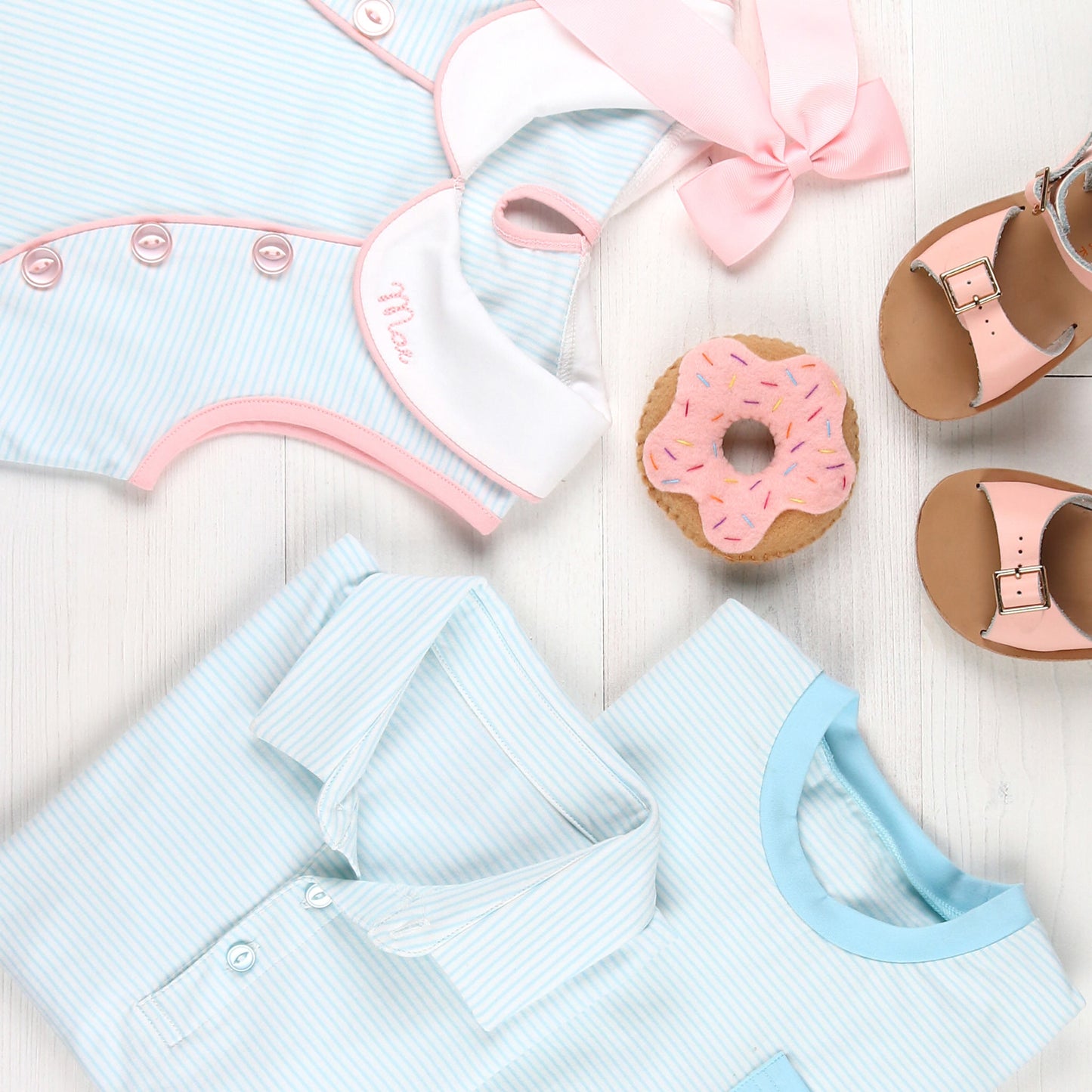 flatlay of Tennis Club Stripe Polo, toy cloth donut, pink sandals, pink hairbow and a dress