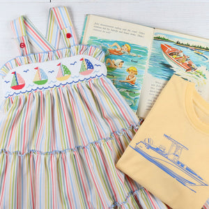 flatlay with a smocked dress, book, and Out To Sea Graphic Tee