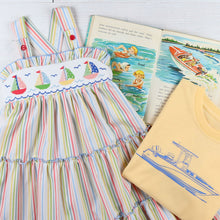 Load image into Gallery viewer, flatlay of sailboat dress, tshirt and a book