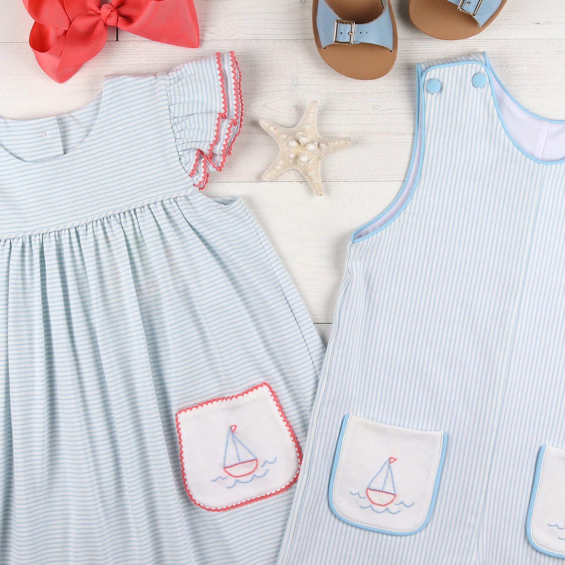 flatlay of striped dress, striped jumper, red bow and blue sandals