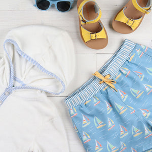 flatlay of beach cover up, sandals and bathing suit