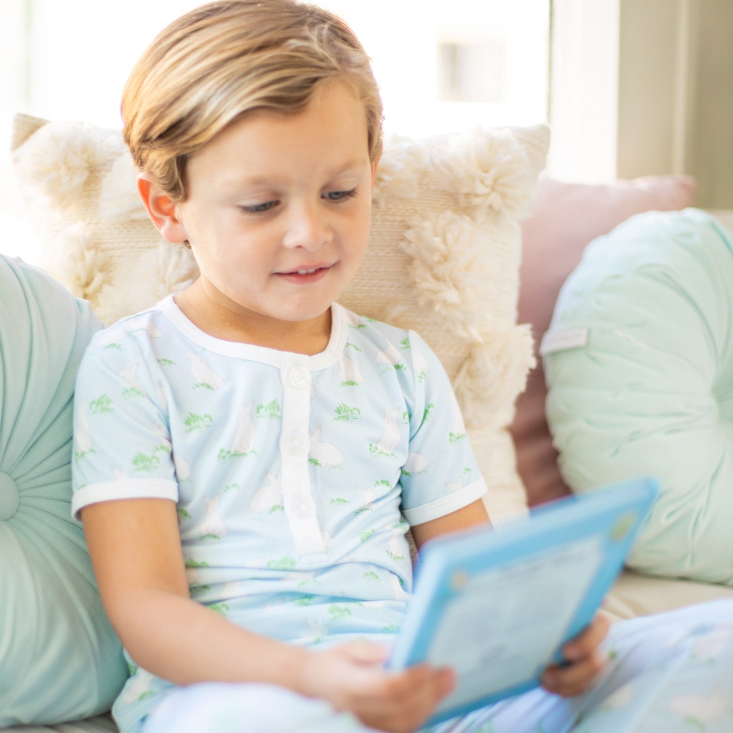 little boy reading a book on a couch
