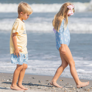 little girl and little boy walking down the beach together