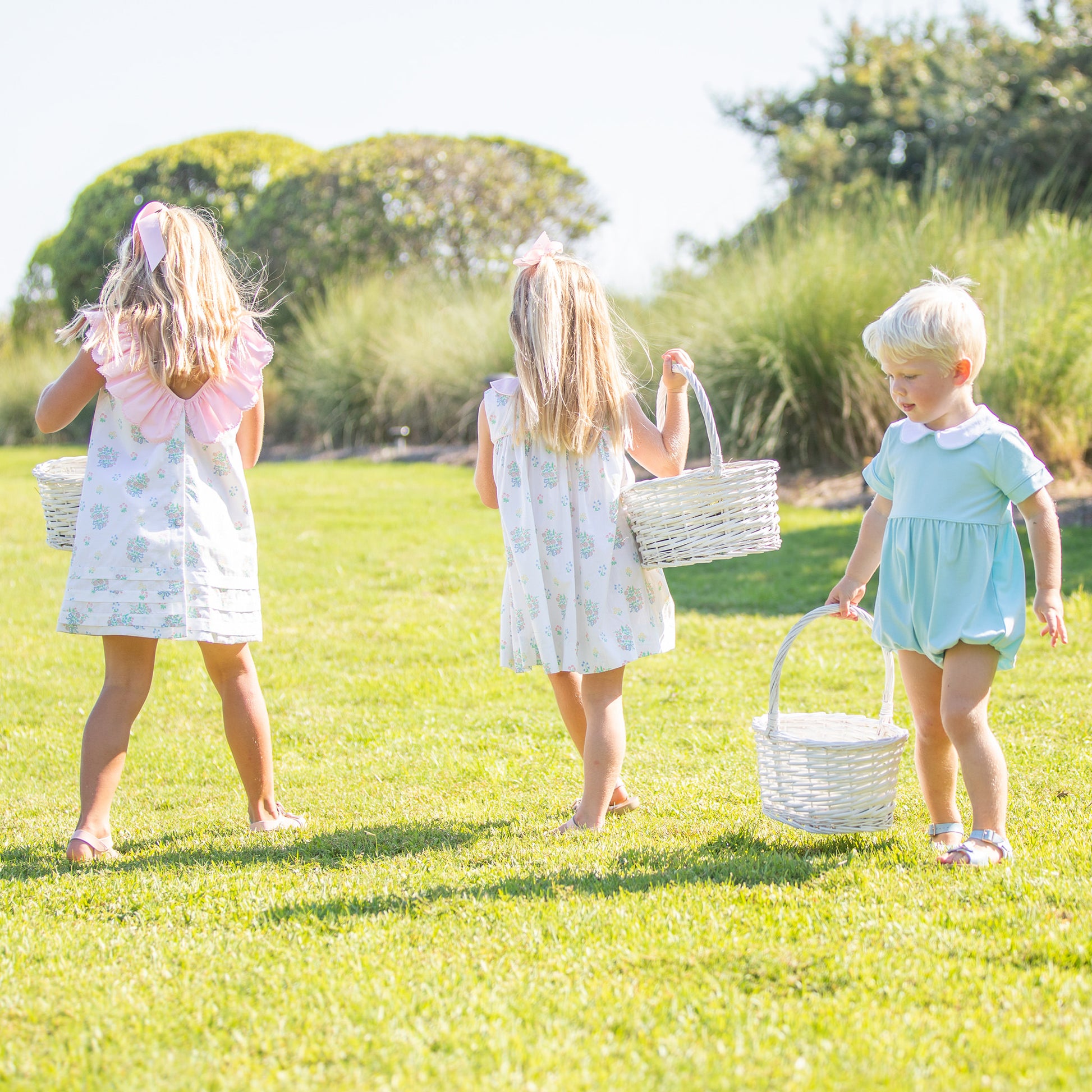 2 little girls and a little boy wearing Briggs Blue Knit Romper Bubble at an easter egg hunt