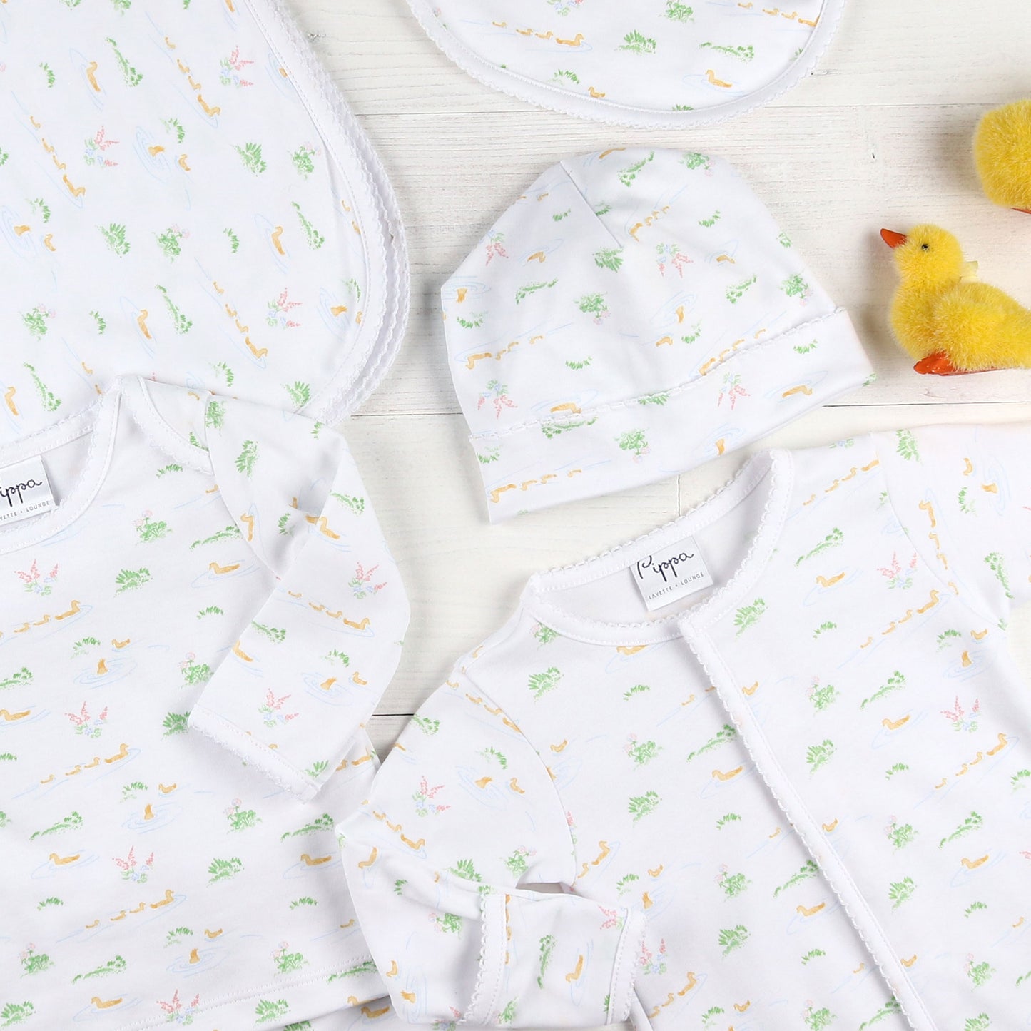 flatlay of Ducky Pima Baby Lounge Set with baby hats