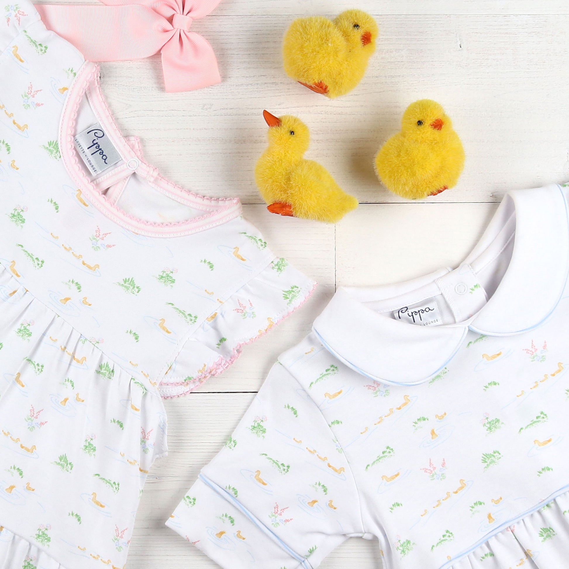 flatlay of Ducky Pima Flowy Dress, jumper, pink bow and yellow cloth ducks
