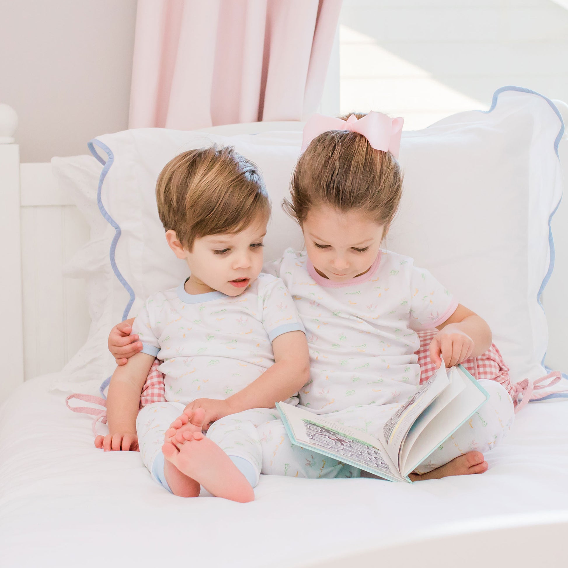 little boy and little girl reading a book on a bed