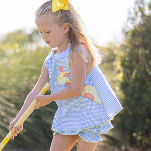 little girl playing croquet with a yellow bow in her hair