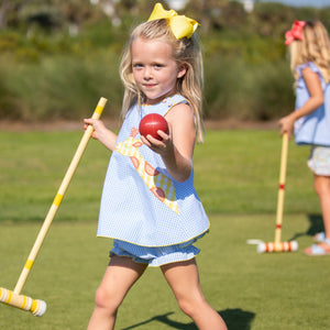 little girl playing croquet in her Sunny Giraffe Applique Swing Set