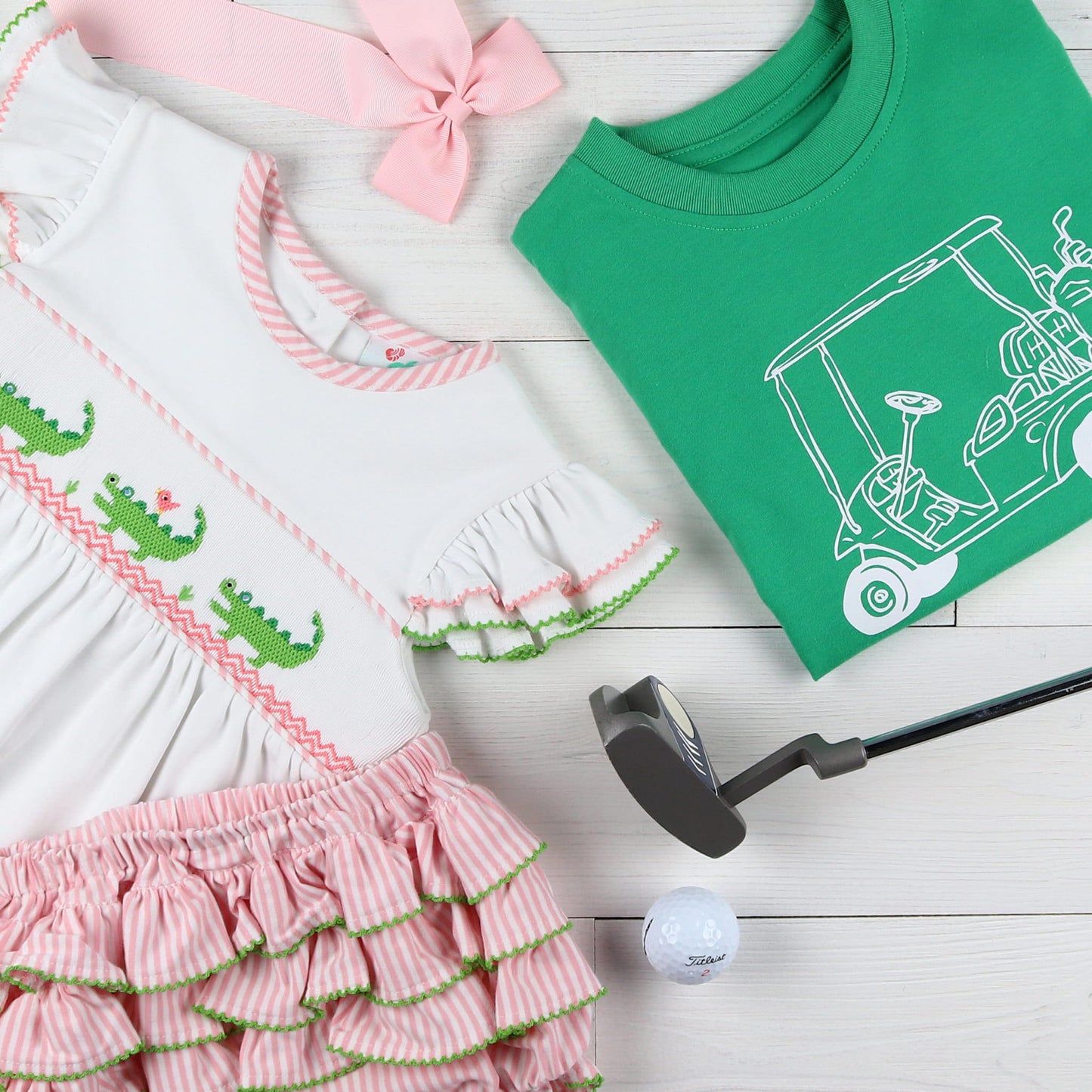 flatlay of green shirt with golf club and pink bow