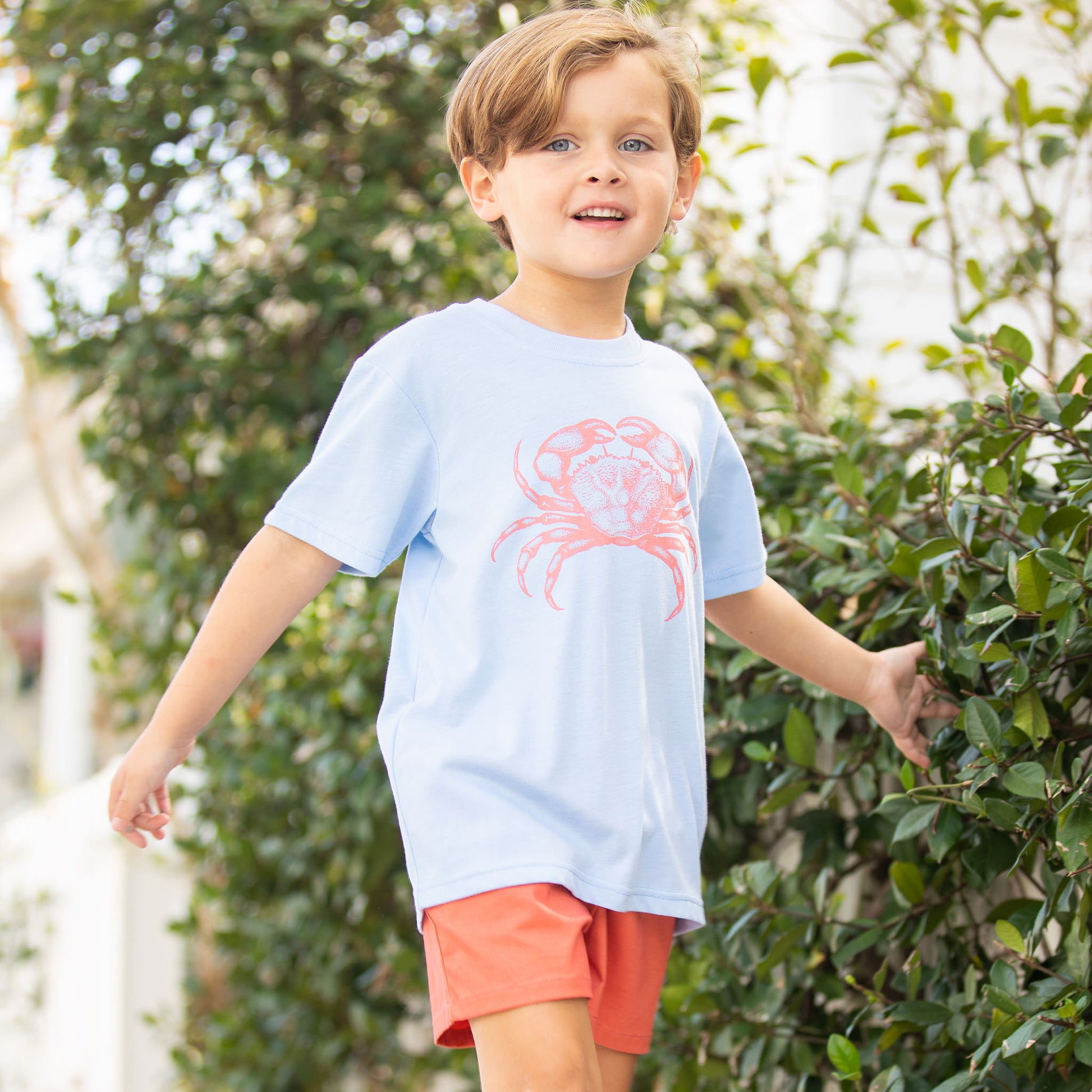 little boy wearing a Crab Graphic Tee walking down the sidewalk smiling