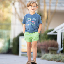 Load image into Gallery viewer, little boy smiling on the sidewalk wearing a Dinosaur Graphic Tee and green shorts