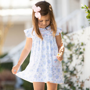 little girl wearing dress and holding a flower walking down the sidewalk