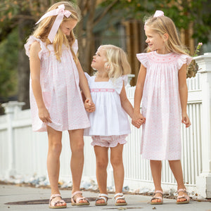 little girl wearing Girls Petit Rose Smocked Bloomer Set and smiling at her sisters