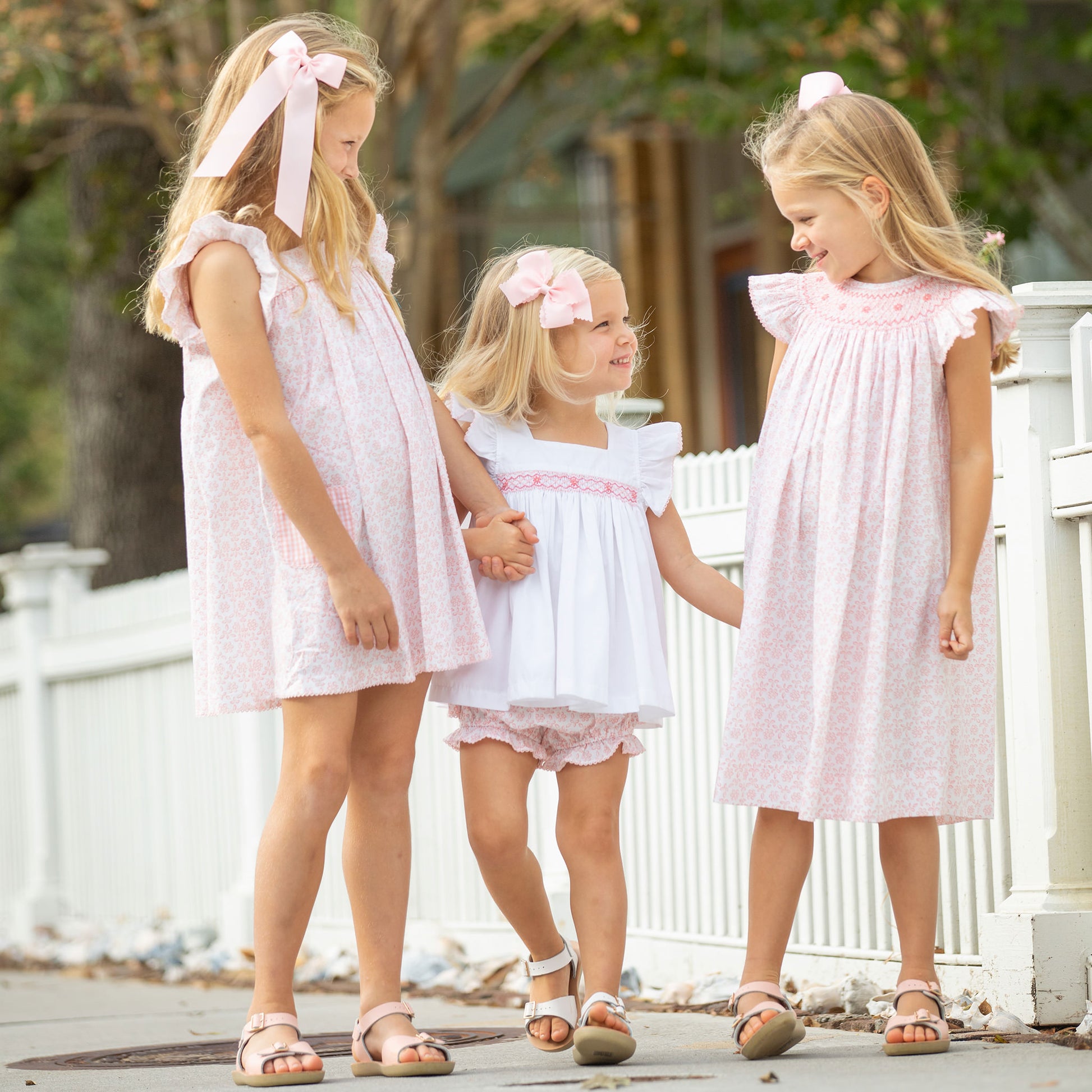 little girls smiling at each other on the sidewalk