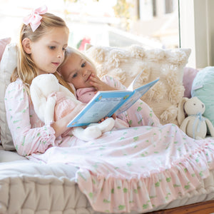 2 little girls reading a book together on a couch