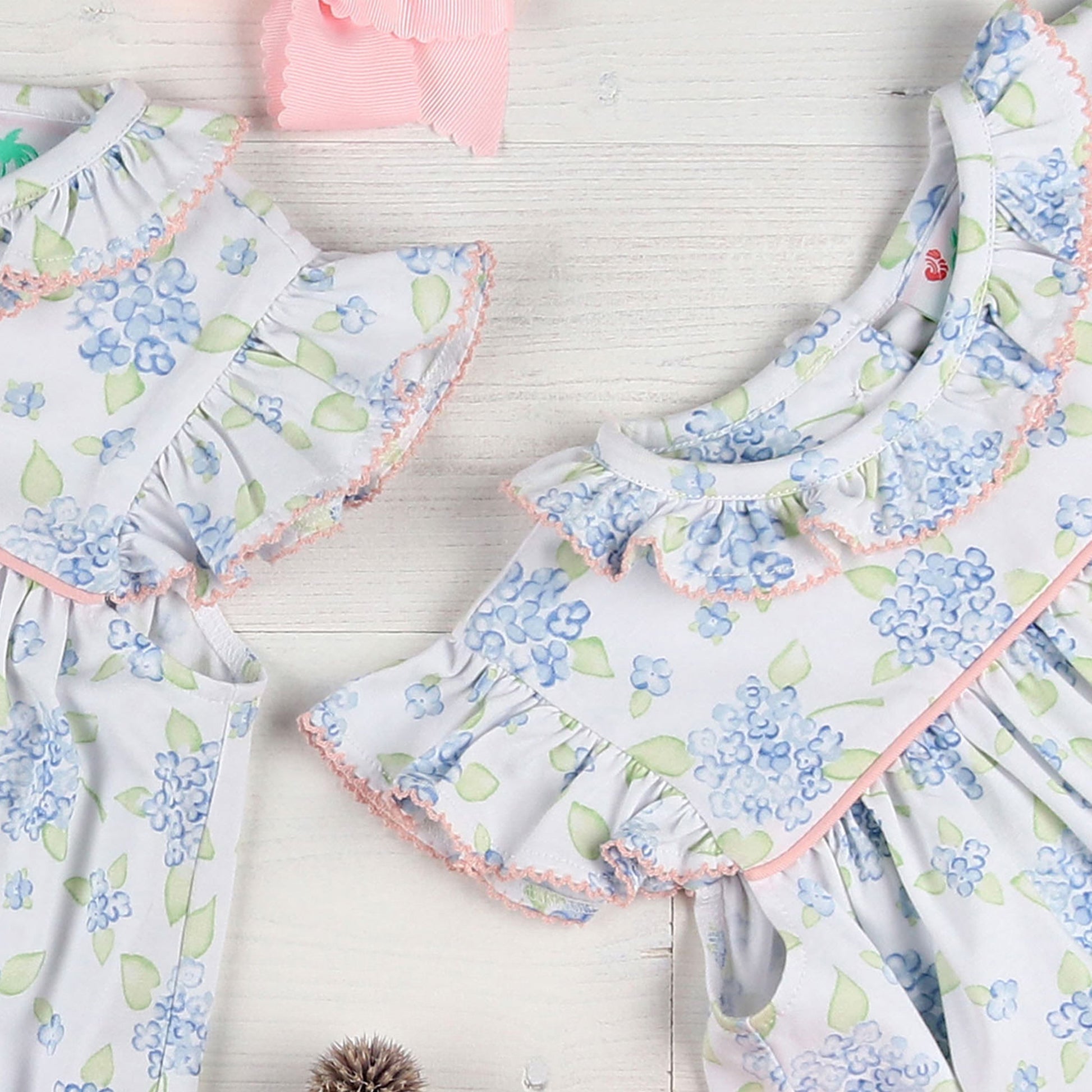 flatlay of two dresses and a pink bow