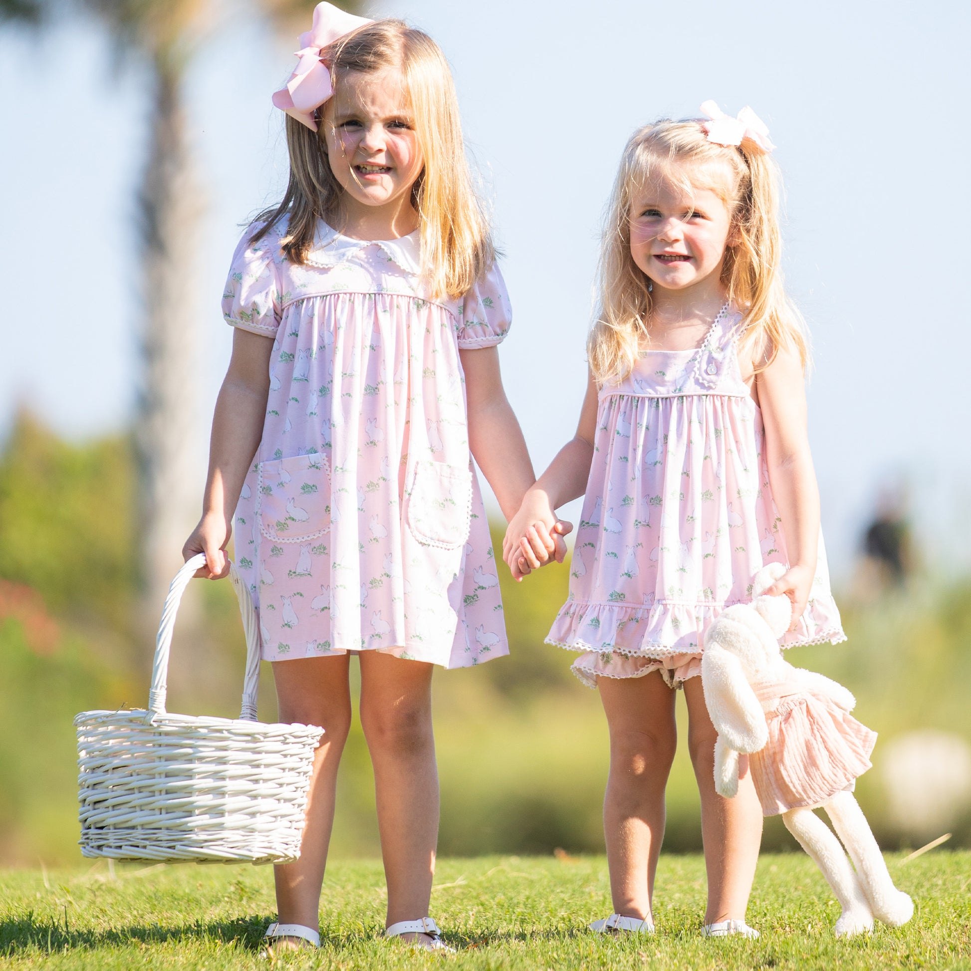 a little girl wearing a Hippity Hoppity Knit Set holding hands with her sister holding an easter basket and stuffed bunny rabbit