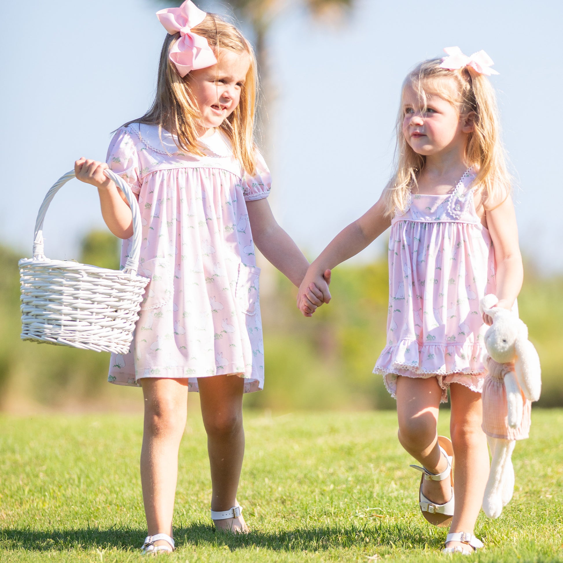 little girl wearing Hippity Hoppity Knit Dress and holding hands with another little girl at an Easter egg hunt