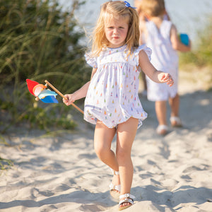 little girl holding a pinwheel walking on the beach