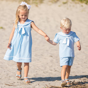 little boy wearing Boys Sail Away Set holding his sister's hand on the beach