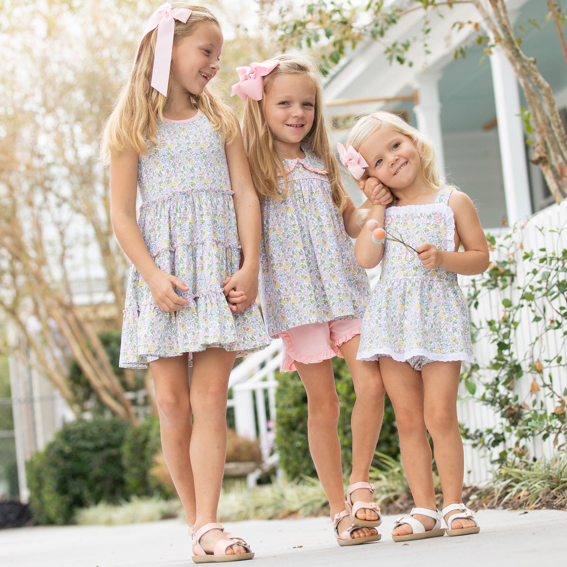 three little girls smiling and one is wearing Tybee Floral Tier Dress