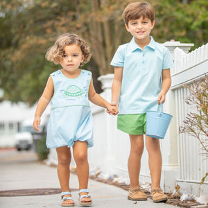 a little boy and his brother (wearing Briggs Blue Knit Polo) holding hands and walking down a neighborhood sidewalk together