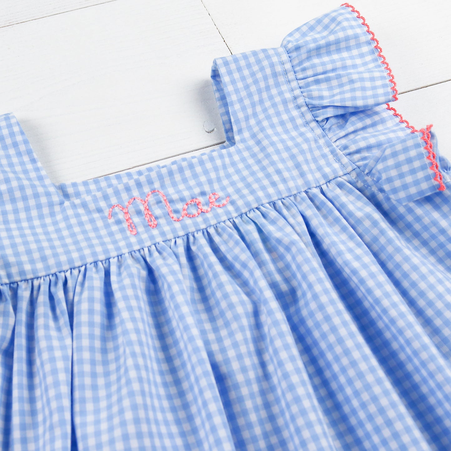 close up of an embroidered name on a blue checked dress