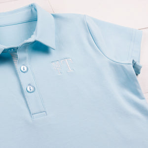 close up of a monogram on a light blue polo shirt