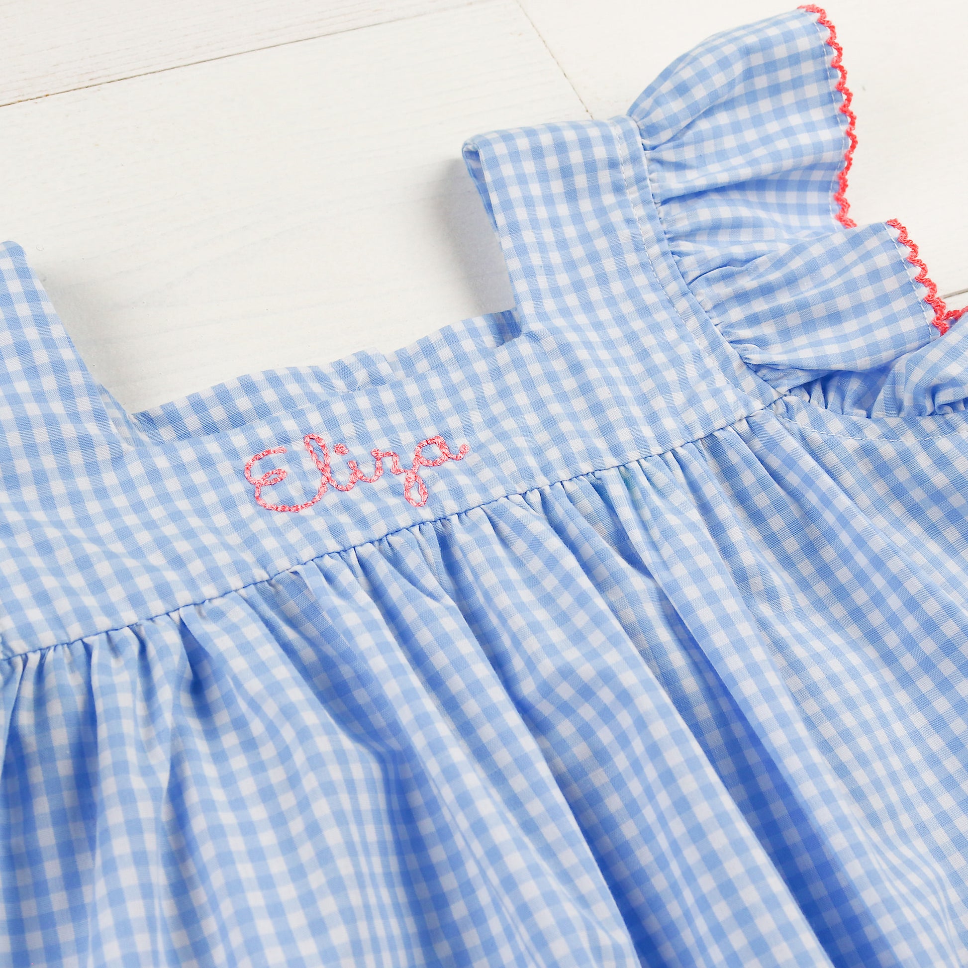 close up of a monogram on a blue and white gingham dress
