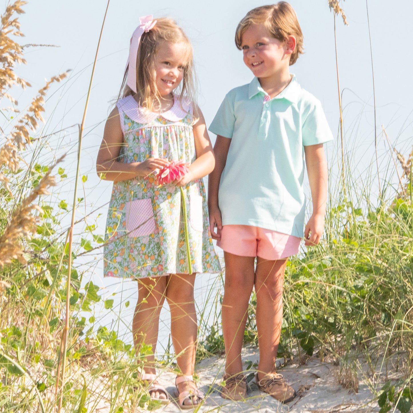 little girl standing next to a little boy wearing a in the dunes on the beach